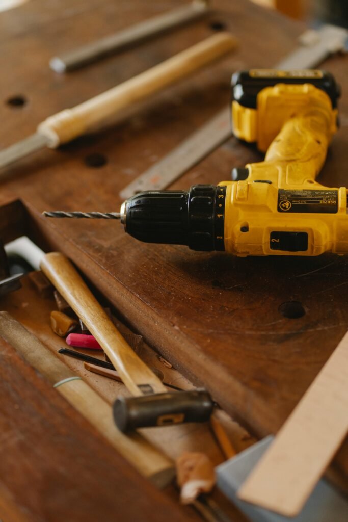 pexels-photo-5974048-5974048 From above of contemporary screwdriver with drill near hammer and tools on wooden desk